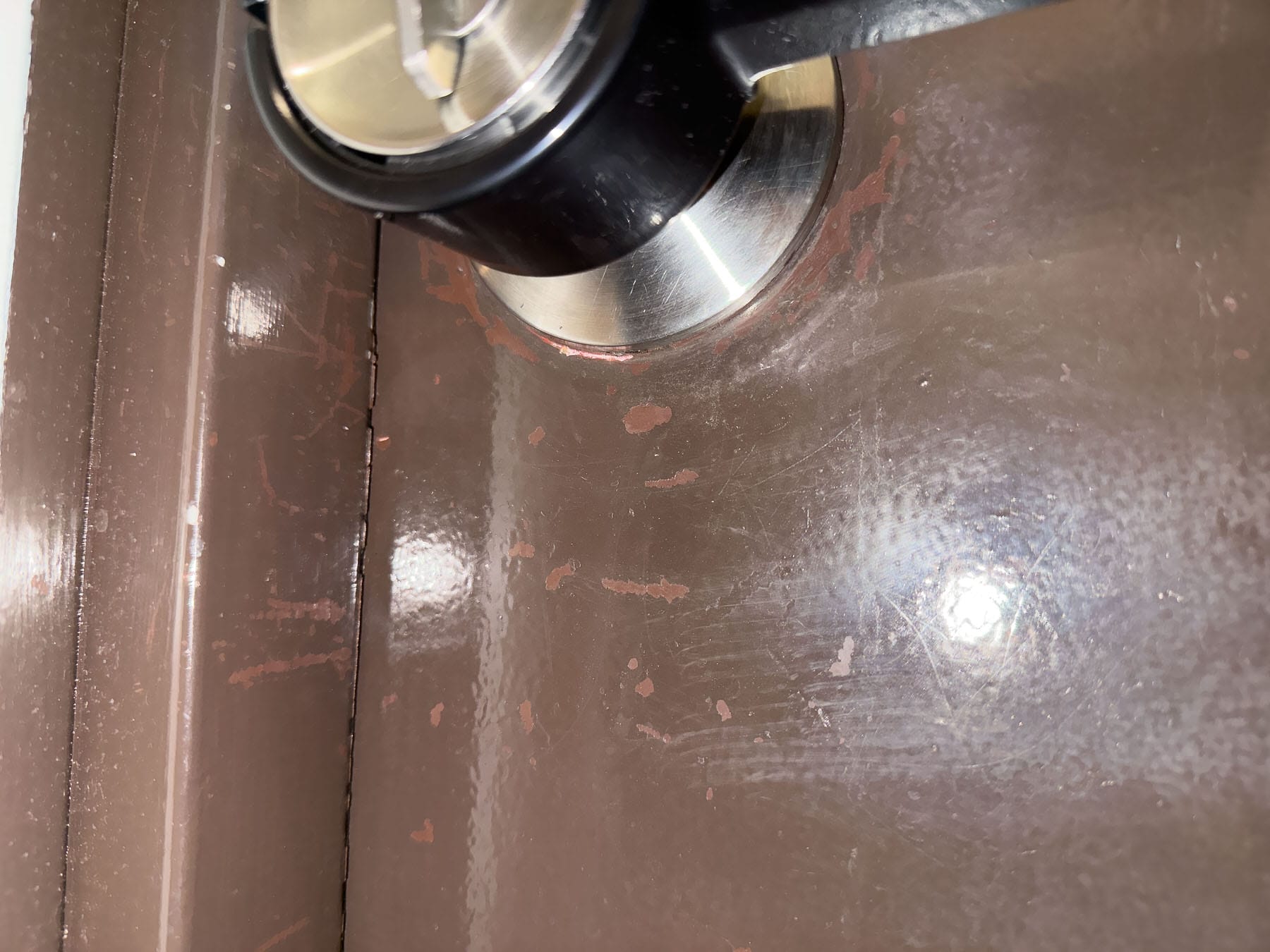 画像 築古ドアの表面。ドアノブ周辺のペンキが剥がれてサビが露出している