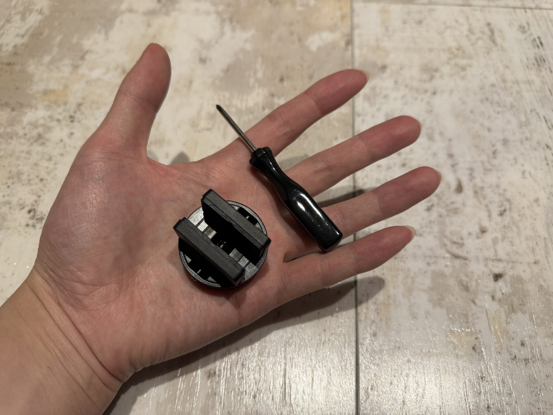 画像 SwitchBot ロックProのサムターンアダプターと付属ドライバーを手のひらに載せた様子